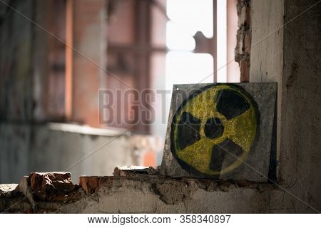 Old Radiation Sign On Rusty Metal Plate On The Abandoned Building Window Background.