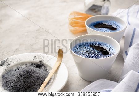 Blue Matcha Tea In Two White Cup , Wooden Tray, Bamboo Tavan And Tasaku, Powder On White Gray Backgr