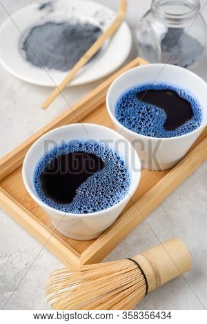 Blue Matcha Tea In Two White Cup , Wooden Tray, Bamboo Tavan And Tasaku, Powder On White Gray Backgr