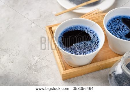 Blue Matcha Tea In Two White Cup , Wooden Tray, Bamboo Tavan And Tasaku, Powder On White Gray Backgr