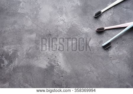 Flat Lay Composition Of Multi-colored Toothbrushes On A Gray Background With Space For Text.