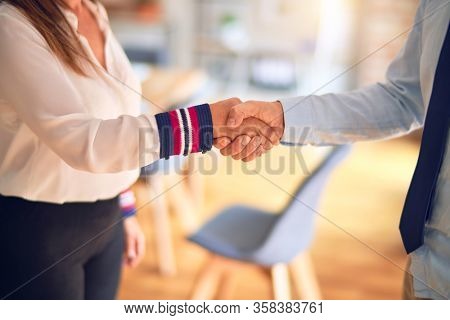 Two middle age business workers working together doing handsake at the office