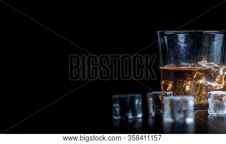 Whisky, Whiskey, Bourbon Or Cognac With Ice Cudes On Black Stone Table