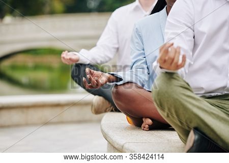 Cropped Image Of Young Business People Sitting In Lotus Position Keeping Hands In Shuni Mudra