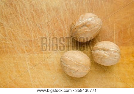 Three Walnuts On Vintage Wooden Cutboard With Knife Marks. Copy Space.