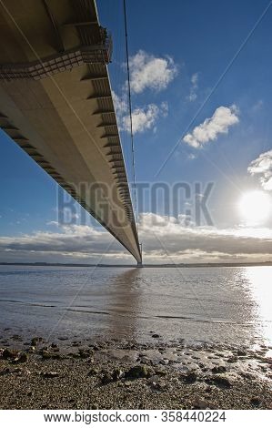 Large Suspension Bridge Spanning A Wide River Estuary On A Clear Day With Blue Sky And Clouds
