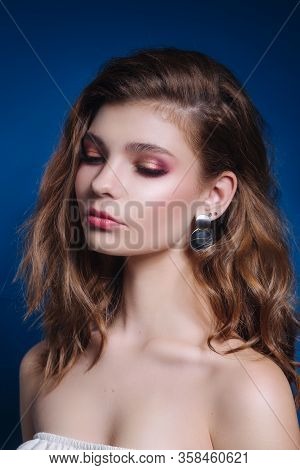 Lbeautiful Woman Model With Curly Hairstyle And Evening Make-up Looking Sideways On Blue Background