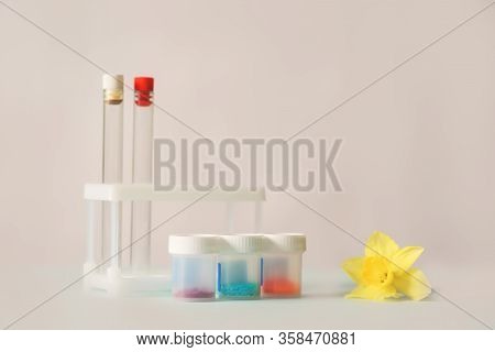 Glass Medical Flasks, Jars With Chemicals And A Yellow Daffodil Flower On A Light Background