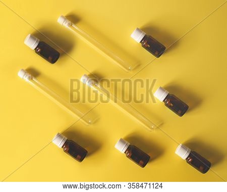 Abstract Background Glass Test Tubes Lie With Vials Of Medicine On A Yellow Background. Medicine, Va