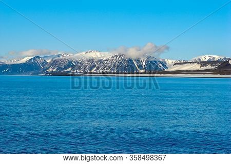 A View Of The Arctic Island From The Sea, Beyond The Ocean, You Can See The Shore, The Mountains Cov