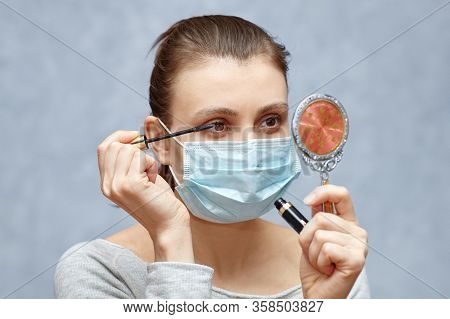 Young Woman Does Make Up With Macsara Brush, Loking Into The Small Hand Mirror. Sterilized Hygienic 