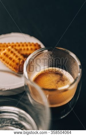 One Portion Of Espresso In Glass Transparent Cups, Bisuits And Water On A Dark Stone Background