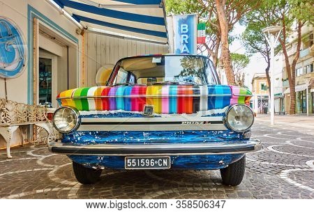 Cattollca, Rimini, Italy - February 29, 2020:  Front view of colorful vintage car NSU Prinz L parked next to Brandina store in small italian town