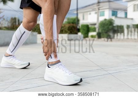 Close Up On Ankle Injury. The Man Use Hands Hold On His Ankle While Running