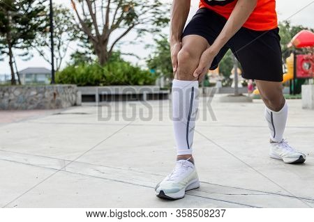 Close Up On Knee Injury. The Man Use Hands Hold On His Knee While Running In The Park