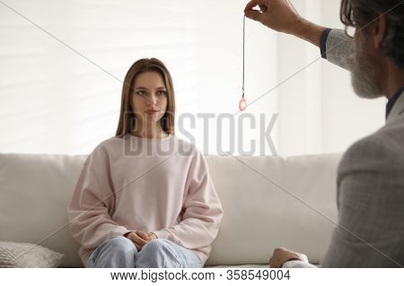 Psychotherapist Using Pendulum During Hypnotherapy   Session In Office