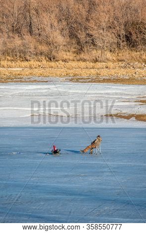 Saskatchewan Landing, Sk, Canada- March 29, 2020: Male Fisherman Ice Fishing On Lake Diefenbaker