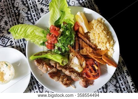 Traditional Turkish Lunch. Grilled Lamb Kebab On Wooden Skewers With Side Dish And Slice Of Lemon On