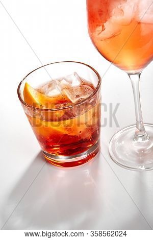 Negroni cocktail close up. Alcohol strong aperitif drink in glass side view. Beverage with red vermouth, Campari liqueur, gin, orange and ice in drinkware. Italian cocktail portion in glassware