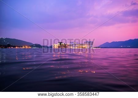 Romantic luxury India travel tourism - Lake Palace (Jag Niwas) complex on Lake Pichola on sunset in twilight with dramatic sky, Udaipur, Rajasthan, India