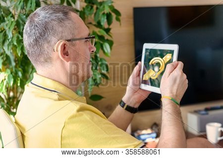 Man wearing deaf aid in ear with tablet showing deaf sign an the display. Concept of using tablets and smartphones by deaf and with hearing impairment people