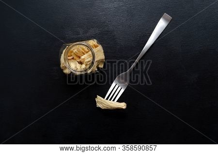 Flatlay Of Fermented Soy Tofu Yuba Leather With In A Jar And On A Fork On A Black Slate Background. 