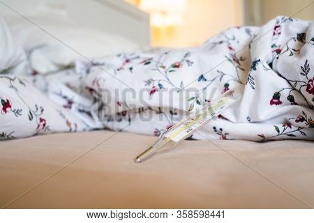  thermometer in bed showing fever coronavirus or COVID-19 