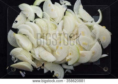 Top View Of Cutted In Half Lengthwise Onion Strips On The Black Background