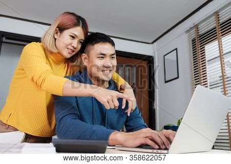 Asian Couple Watching Video Live Straming On Laptop At Table At Home.lover Spending Time Together.ta