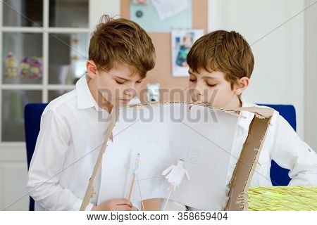 Two Little School Kids Boy Making Paper Doll Theatre. Happy Children And Friends Creating Figures An