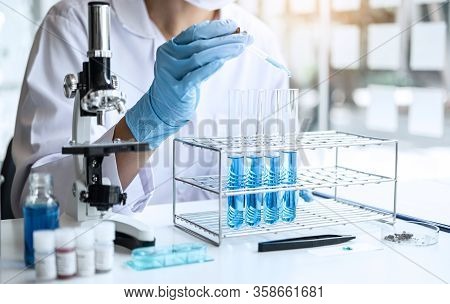 Biochemistry Laboratory Research, Scientist Or Medical In Lab Coat Holding Test Tube With Using Micr