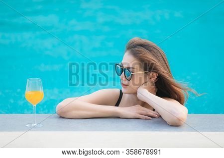 Beautiful Asian Woman Wear Bikini And Sunglasses Standing In Blue Water Pool With Relax Manner, Look