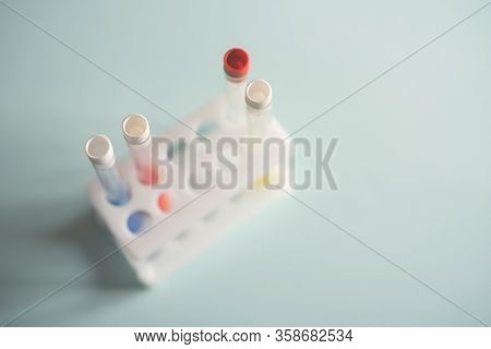Glass Medical Flasks, Jars With Chemicals And A Yellow Daffodil Flower On A Light Background