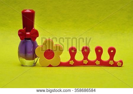 A Bottle Of Purple Nail Polish With A Toe Separator
