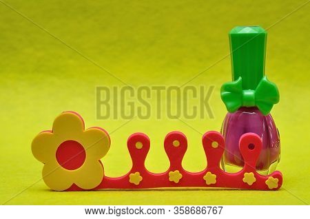 A Bottle Of Pink Nail Polish With A Toe Separator