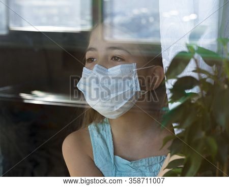 Stay At Home Quarantine Coronavirus Pandemic Prevention. Sad Child In Protective Medical Mask Looks 