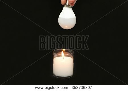 Innovation - Close-up, Candle And New Economical Light Bulbs On A Black Background.