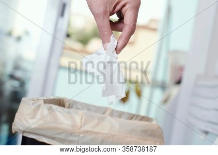 closeup of a young caucasian man indoors about to throw a used wet wipe to the trash bin