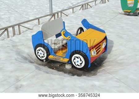 Childrens Swing In The Form Of A Car On The Playground Against The Background Of Winter Snowdrifts. 