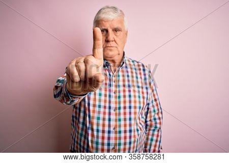 Senior handsome hoary man wearing casual colorful shirt over isolated pink background Pointing with finger up and angry expression, showing no gesture