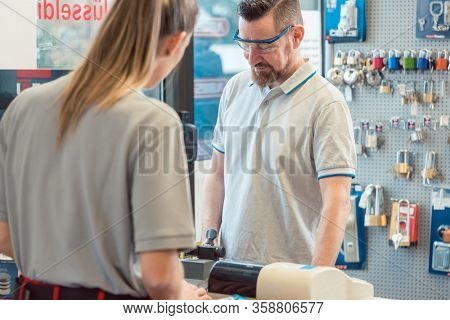 Woman customer talking to keymaker or locksmith in his shop