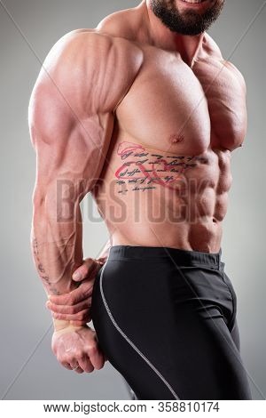 Close Up Of Sexy Muscular Bodybuider Posing On The Gray Background. Triceps, Pectoral Muscle And Abs