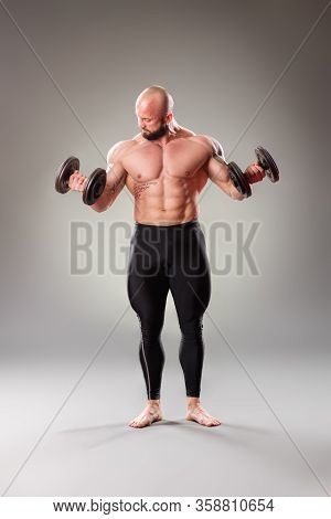 Sexy Muscular Bodybuider Posing With Weights On The Gray Background