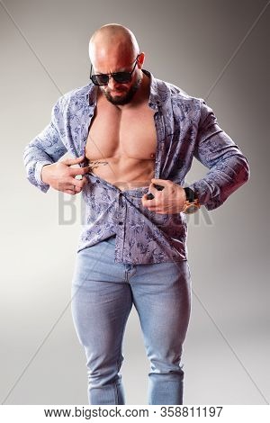 Sexy Unbuttoned Muscular Bodybuider With Sunglasses On The Gray Background