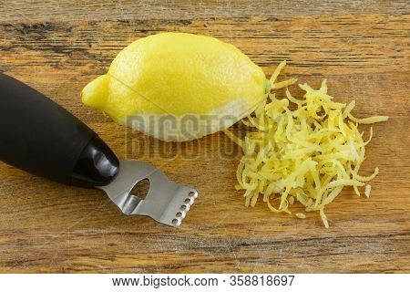 Lemon With Pile Of Lemon Zest And Zester On Wooden Cutting Board