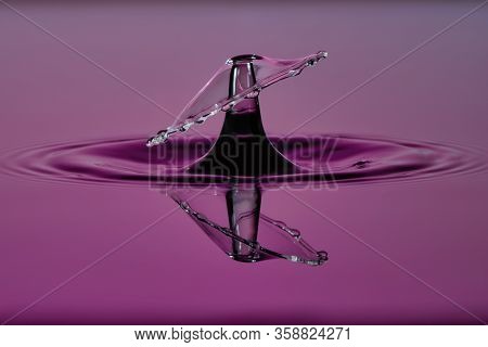 Two Transparent Water Drops Collide To Form An Umbrella Shape With A Reflection On The Water Surface