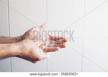 Man Cleaning His Hands Using Liquid Disinfectant Soap And Water In Bathroom.