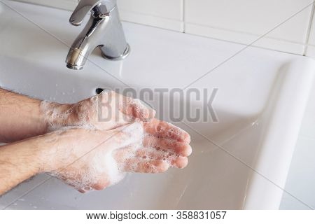 Man Cleaning His Hands Using Liquid Disinfectant Soap And Water In Bathroom.