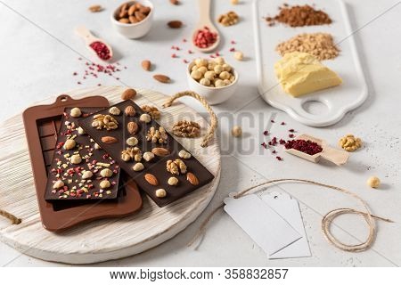 Variety Of Chocolate Bars, Nuts And Ingredients On White Wooden Background. Side View