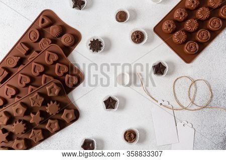 Raw Vegan Handmade Chocolate Candies And Different Molds On White Concrete Background. Top View, Fla